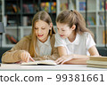 School children sitting at desk together, reading funny book and laughing, friends having fun in class. Pupils studying in class. Concept of education 99381661