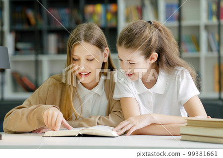 School children sitting at desk together, reading funny book and laughing, friends having fun in class. Pupils studying in class. Concept of education School children sitting at desk together, reading funny book and laughing, friends having fun in class. Pupils studying in class. Concept of education 99381661