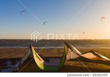 Kite surfers on the water and one close up kite at sunset 99382439