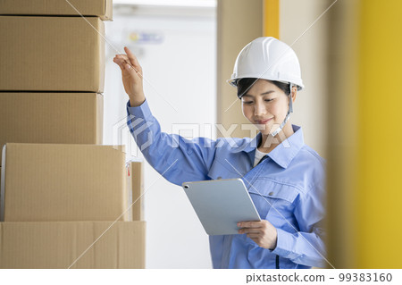 Warehouse management staff image A woman in work clothes holding a tablet 99383160