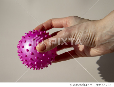 Woman is holding a pink spiked ball. Massage Ball Can Help You Release Knots and Soreness. Benefits of Using a Massage Ball for Myofascial Release Woman is holding a pink spiked ball. Massage Ball Can Help You Release Knots and Soreness. Benefits of Using a Massage Ball for Myofascial Release 99384728