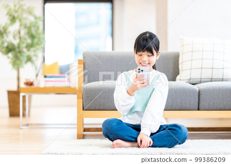 Girl operating a smartphone in the living room 99386209