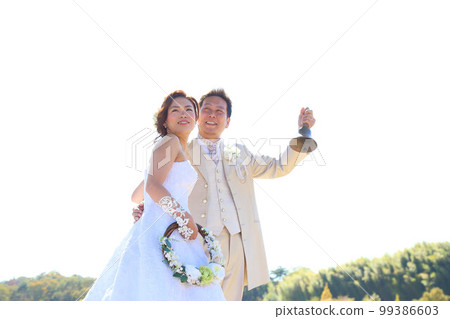 Location shooting of the bride and groom in a wedding dress and tuxedo in a refreshing lawn park Location shooting of the bride and groom in a wedding dress and tuxedo in a refreshing lawn park 99386603