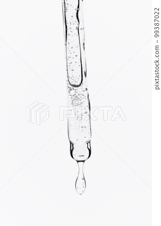 Liquid oil serum drop in pipette isolated on white background. Retinol, aha, bha acid, collagen skincare fluid, photo with shallow depth of field. Hyaluron essence in dropper for beauty treatment 99387022