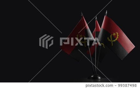 Small national flags of the Angola on a black background 99387498