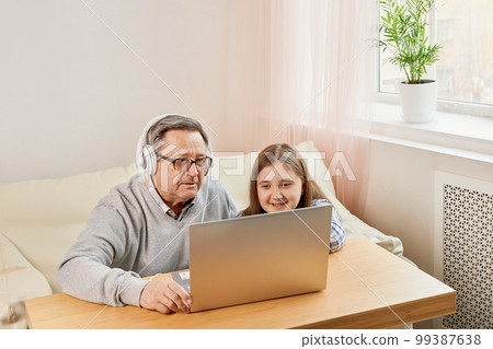 Granddaughter helping grandpa to make on line communication on laptop Granddaughter helping grandpa to make on line communication on laptop 99387638