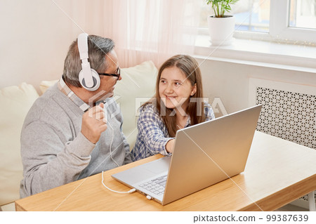 Granddaughter helping grandpa to make on line communication on laptop Granddaughter helping grandpa to make on line communication on laptop 99387639