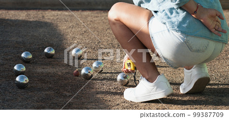Petanque game, woman measuring the distance of petanque ball in petanque field, deciding who's the winner 99387709