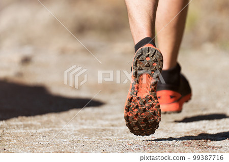 Trail running athlete exercising for fitness and health outdoors on mountain pathway, closeup of running shoes in action 99387716