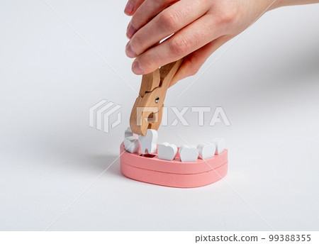 Extraction of tooth from toy jaw model with forceps close up 99388355