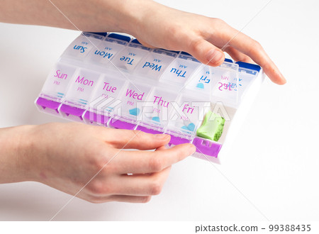 Woman hands opening pill case with natural organic nutrition, vitamin with avocado piece 99388435