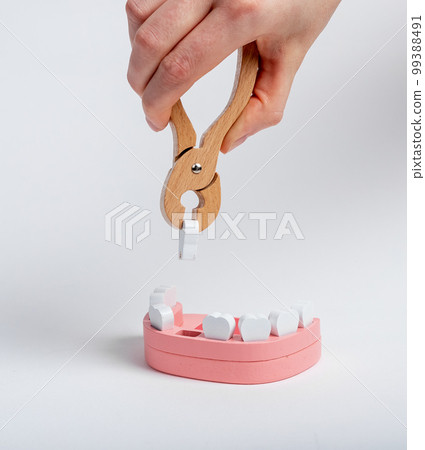 Extracting tooth from jaw model with forceps closeup Extracting tooth from jaw model with forceps closeup 99388491