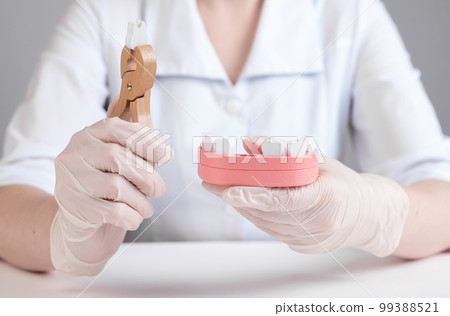 Dentist pulling tooth with forceps out of jaw model. Dental surgeon using instrument for teeth removal, extraction. Stomatology, oral health problems. 99388521