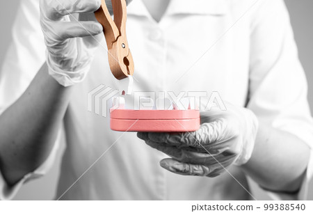 Dentist pulling tooth with forceps out of jaw model. Teeth extraction, loosing, stomatology concept. Work of dental surgeon in lab coat and gloves. 99388540