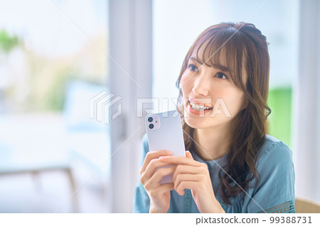 Young woman wearing glasses operating a smartphone at home Young woman wearing glasses operating a smartphone at home 99388731