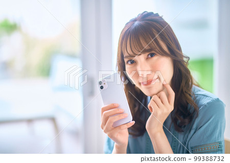 Young woman wearing glasses operating a smartphone at home Young woman wearing glasses operating a smartphone at home 99388732