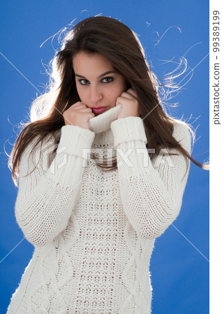 attractive young millennial woman posing on blue background with cold 99389199