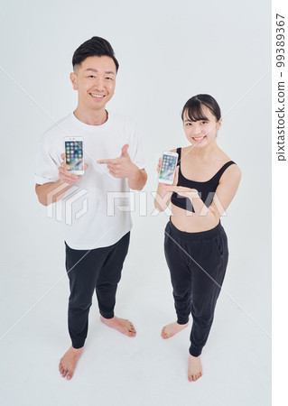 Men and women in sportswear with smartphones Men and women in sportswear with smartphones 99389367
