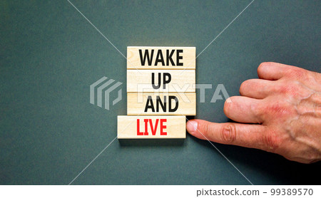 Wake up and live symbol. Concept words Wake up and live on wooden blocks. Beautiful grey table grey background. Businessman hand. Business lifestyle wake up and live concept. Copy space. 99389570