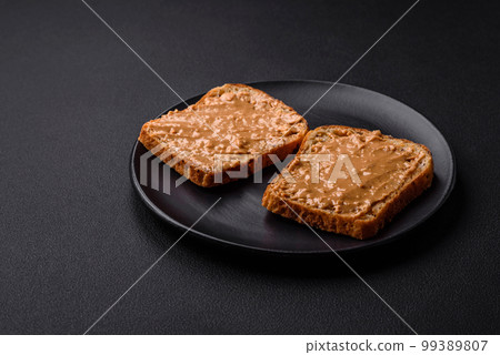 Nutritious sandwich consisting of bread and peanut butter on a black ceramic plate Nutritious sandwich consisting of bread and peanut butter on a black ceramic plate 99389807
