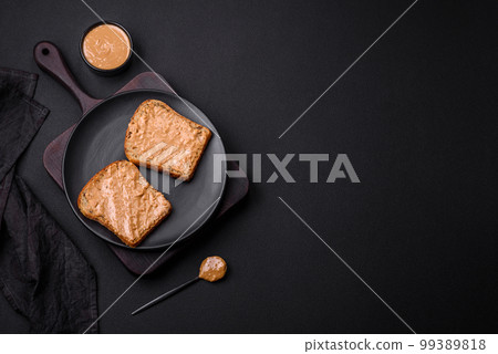 Nutritious sandwich consisting of bread and peanut butter on a black ceramic plate Nutritious sandwich consisting of bread and peanut butter on a black ceramic plate 99389818
