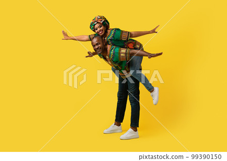 Loving black man, woman having fun on yellow, full length Loving black man, woman having fun on yellow, full length 99390150