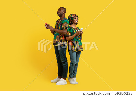 Beautiful loving black couple in traditional costumes using cell phones 99390253