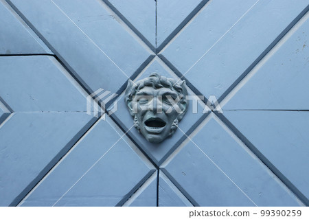 Close up fragment of medieval metal doors with decorative head. 99390259