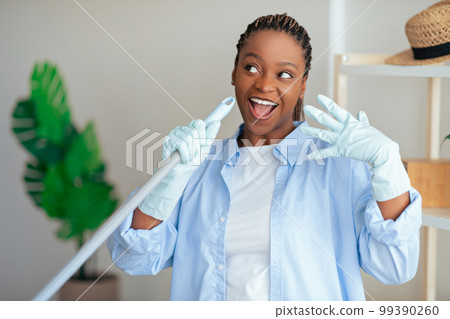 Black woman have fun while cleaning house 99390260