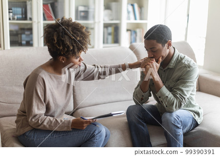 Young african woman psychologist consoling upset man 99390391