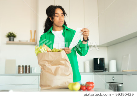 Black Lady Holding Bill Unpacking Bag After Grocery Shopping Indoors 99390429