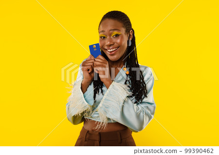 Happy African American Female Holding Credit Card Over Yellow Background Happy African American Female Holding Credit Card Over Yellow Background 99390462