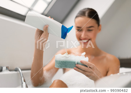 Woman Taking Bath Squeezing Shower Gel On Sponge In Bathroom Woman Taking Bath Squeezing Shower Gel On Sponge In Bathroom 99390482