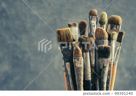 Used paint brushes on gray background. A bunch of brushes for painting with oil and acrylic paints. Artist paintbrushes in a artist studio. 99391240