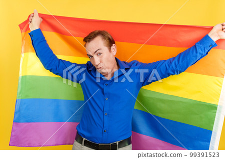 Mature man blowing a kiss raising a lgbt rainbow flag 99391523