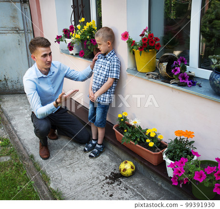 Father reprimands son for breaking flowerpot with ball Father reprimands son for breaking flowerpot with ball 99391930