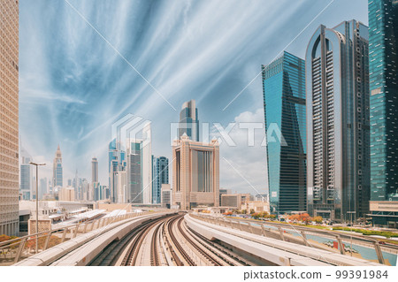 Metro road among glass skyscrapers in Dubai. Metropolitan railway among modern glass skyscrapers in Dubai. Traffic on street in Dubai. Urban background Metro road among glass skyscrapers in Dubai. Metropolitan railway among modern glass skyscrapers in Dubai. Traffic on street in Dubai. Urban background 99391984