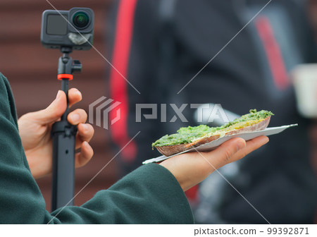 Unidentified man or woman takes a selfie of a snack purchased at the Prague farmers market. 99392871