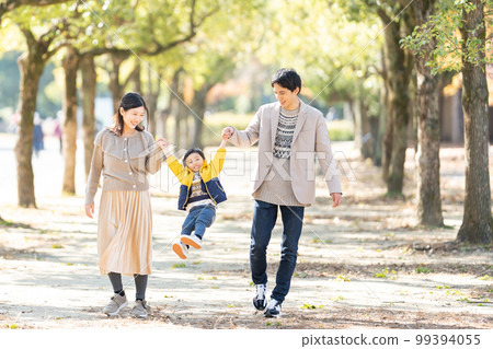 一家人手拉手走在綠樹成蔭的街道上 99394055