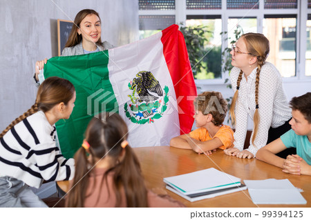 Teacher showing Mexico flag to group of schoolchildren Teacher showing Mexico flag to group of schoolchildren 99394125