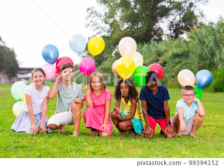 Cheerful tweenagers with colored balloons posing together in summer park 99394152