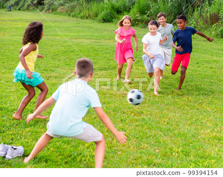Active tweenagers playing football on green grass in summertime 99394154