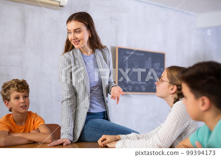 Focused preteens school children listening to young woman teacher during class in auditory Focused preteens school children listening to young woman teacher during class in auditory 99394173