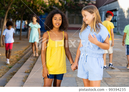 Happy preteen girls walking along city street Happy preteen girls walking along city street 99394235