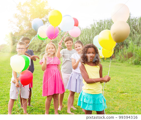 Children with balloons on field 99394316