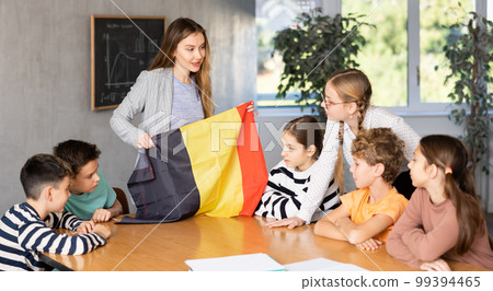 Teacher showing Belgium flag to group of schoolchildren 99394465