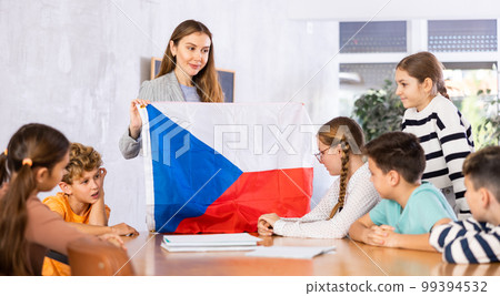 Cheerful female teacher discussing with preteens students state flag of in auditory of middle school 99394532