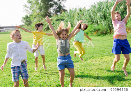 Cheerful preteen girls and boys jumping in summer city park 99394566