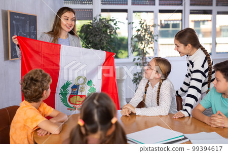 Students sitting in class and listening carefully to female teacher holding Peru flag Students sitting in class and listening carefully to female teacher holding Peru flag 99394617