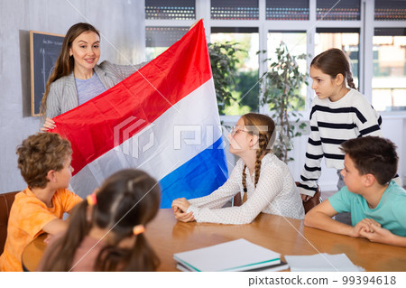 Teacher showing Holland flag to group of schoolchildren Teacher showing Holland flag to group of schoolchildren 99394618